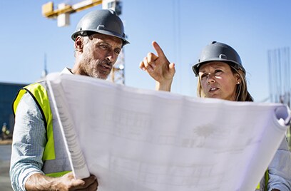 Two architects looking over the blueprint at the construction site