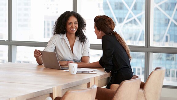 Two women employees sitting in a conference room and discussing