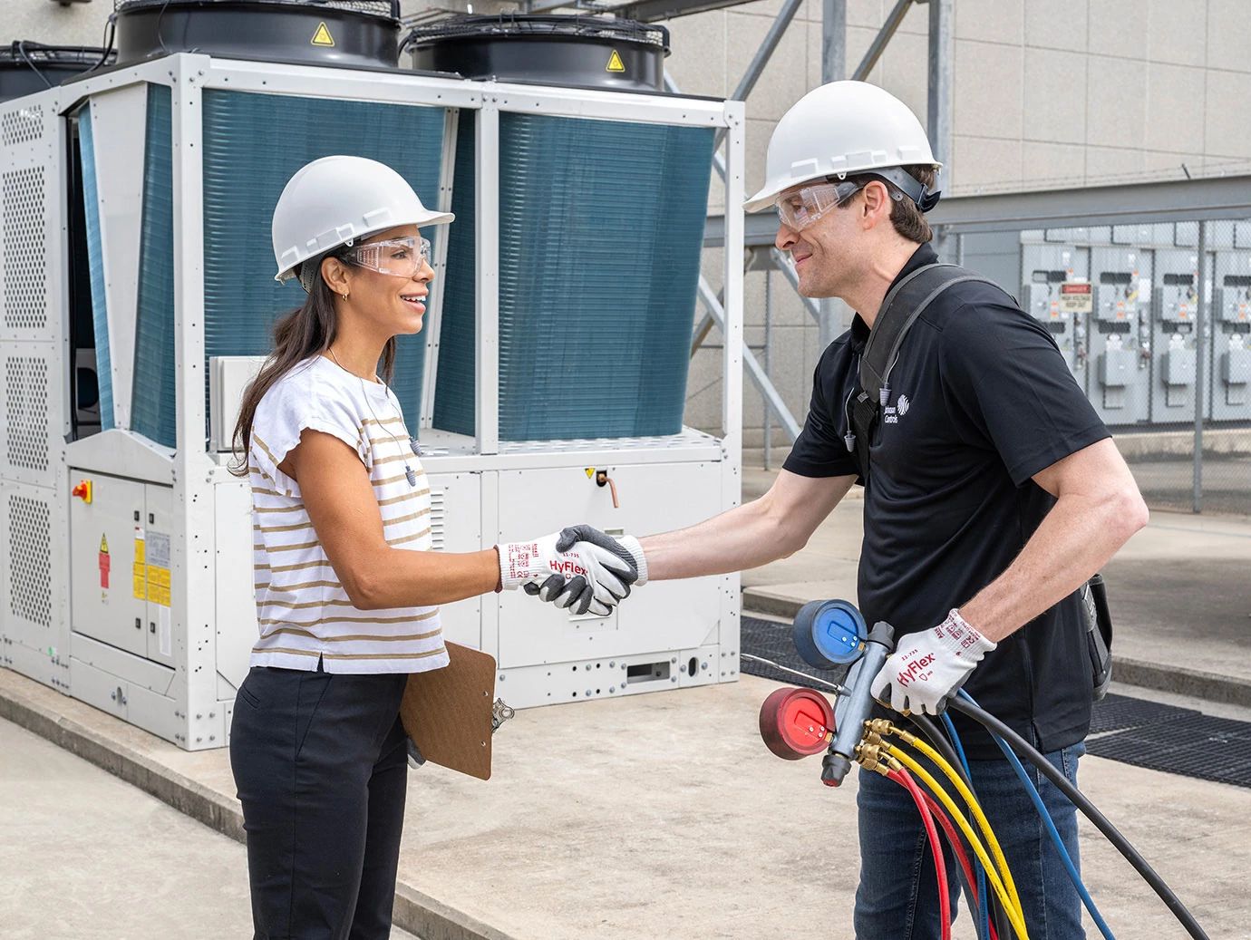 Two workers shaking hands on the floor of a installed chiller plant