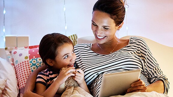 Mother and daughter sitting on the bed and having a conversation in a well lit bedroom