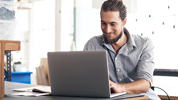 A man working on a desk at his laptop in a workstation