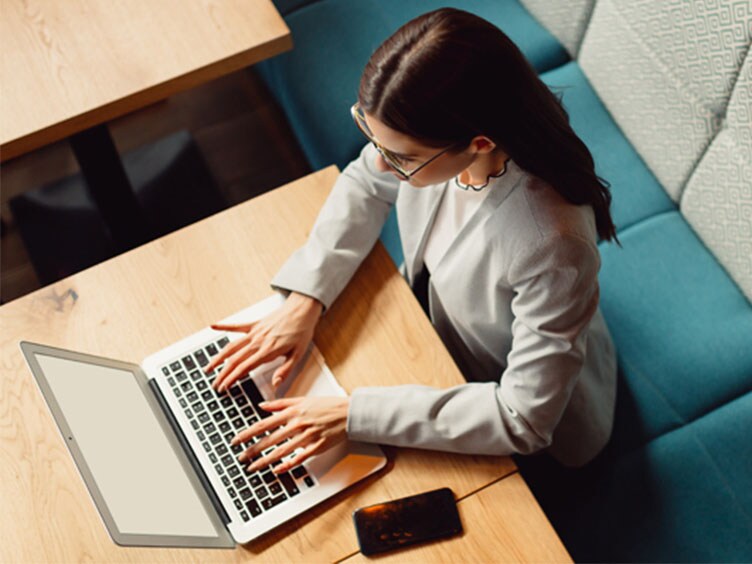 Top view of a lady sitting on sofa and working on her laptop