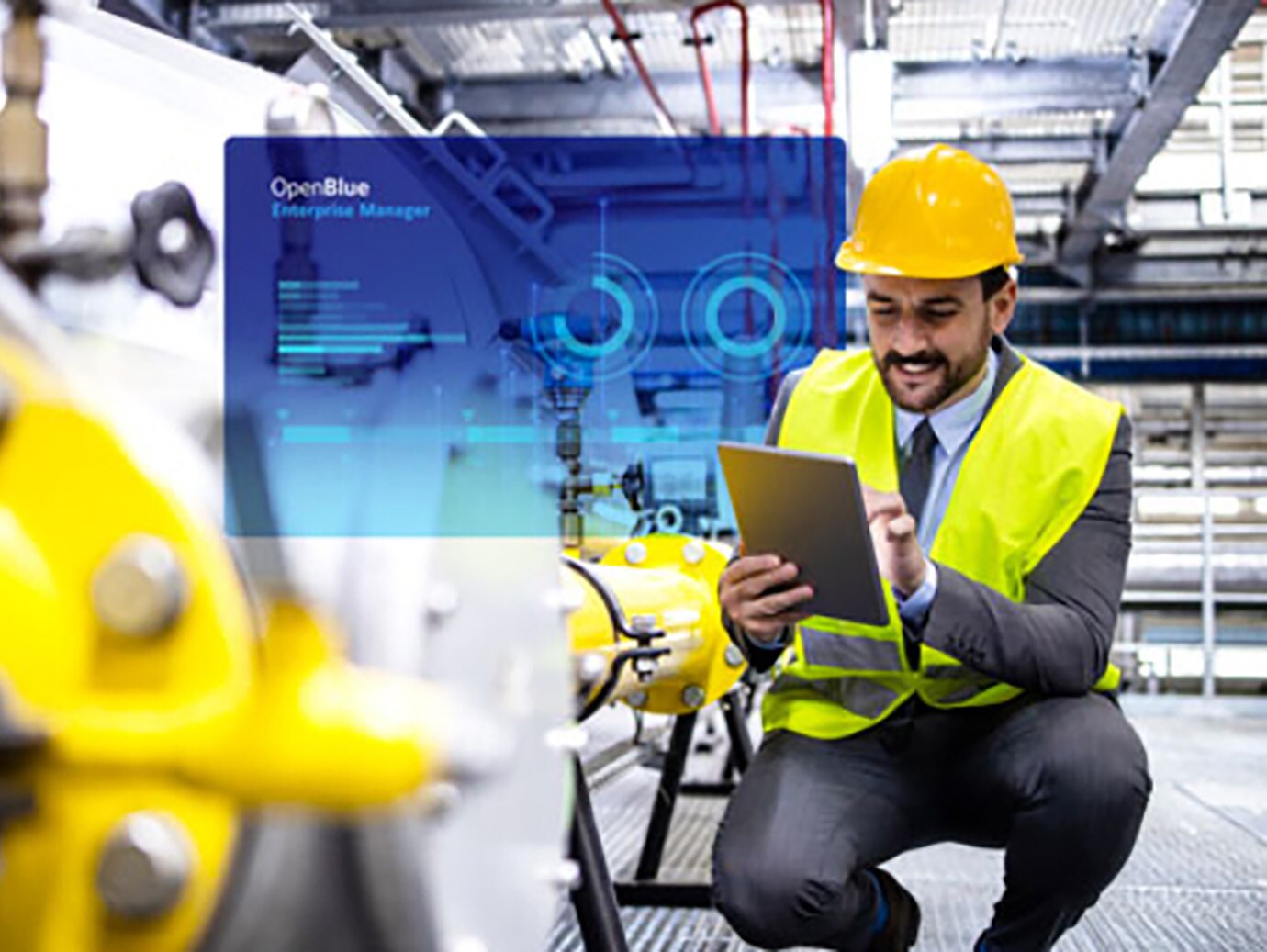 Refinery worker in a safety helmet and reflective vest working on a tab overlaid with graphic depicting Johnson Controls' OpenBlue Enterprise Manager