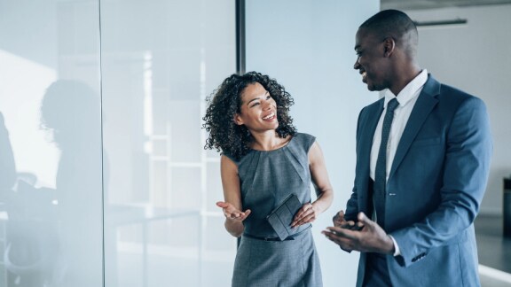 A man and a woman engaged in friendly conversation in an office