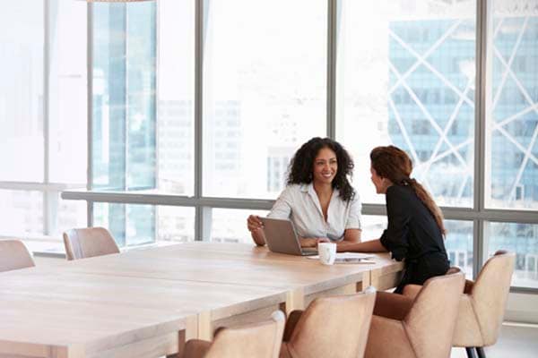 two women conversing at a conference table