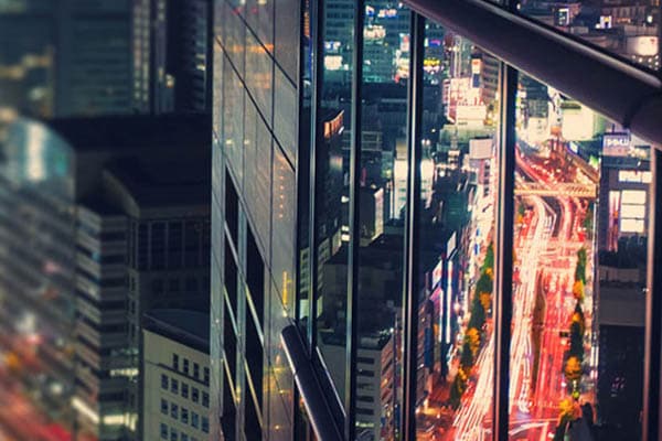 reflection of traffic on a skyscraper at nighttime