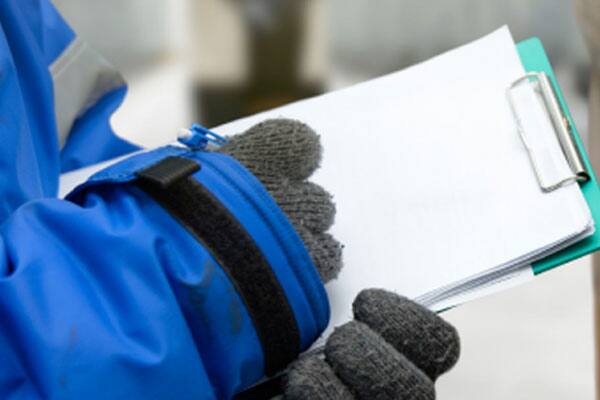 Closeup of a man in uniform writing on a notepad